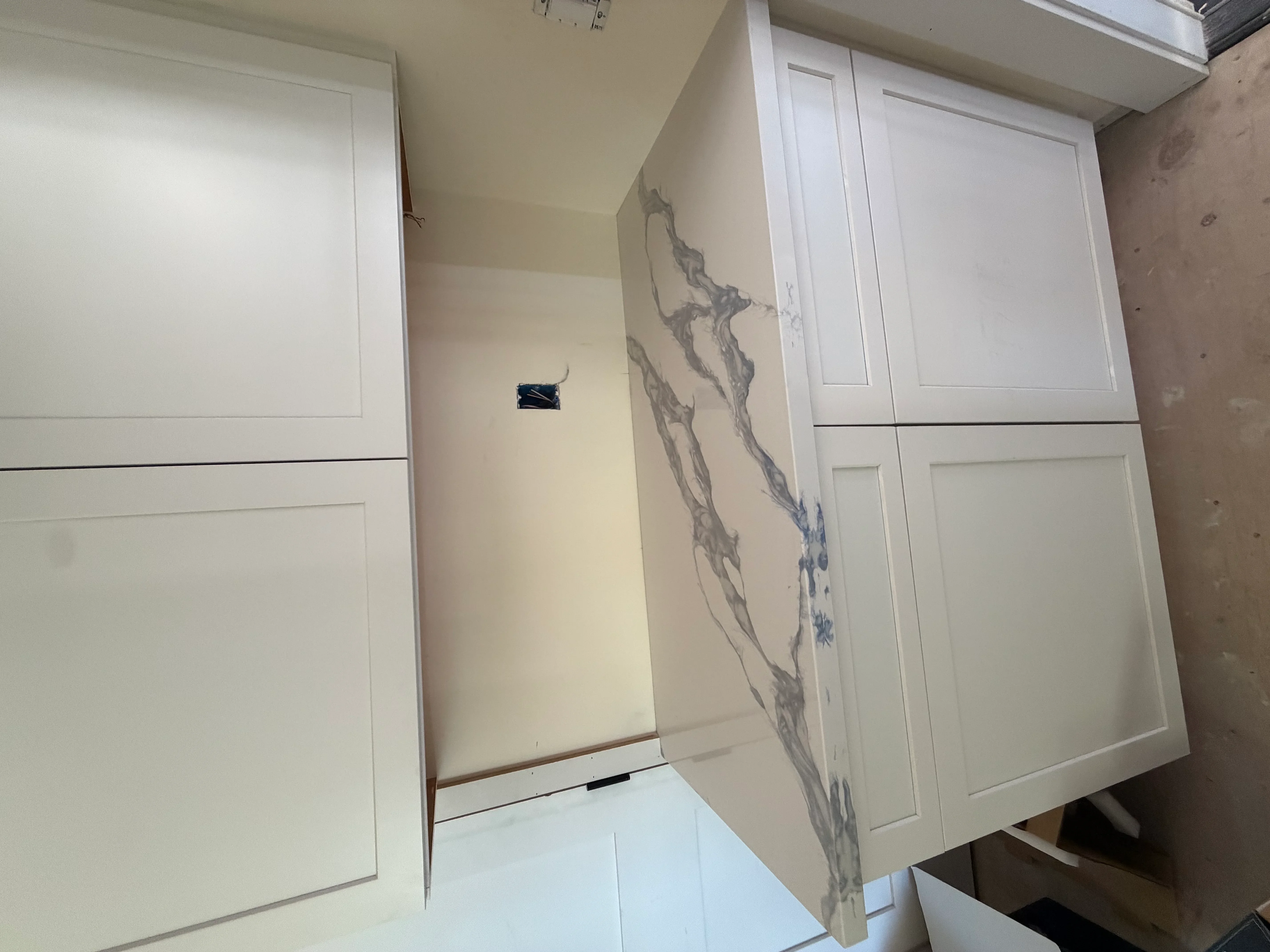 Large marble accent wall with gray and blue veining installed between white cabinetry