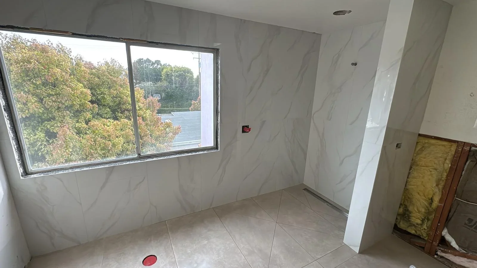 Modern room with marble-look porcelain wall tiles and neutral floor tiles, large window with outdoor view