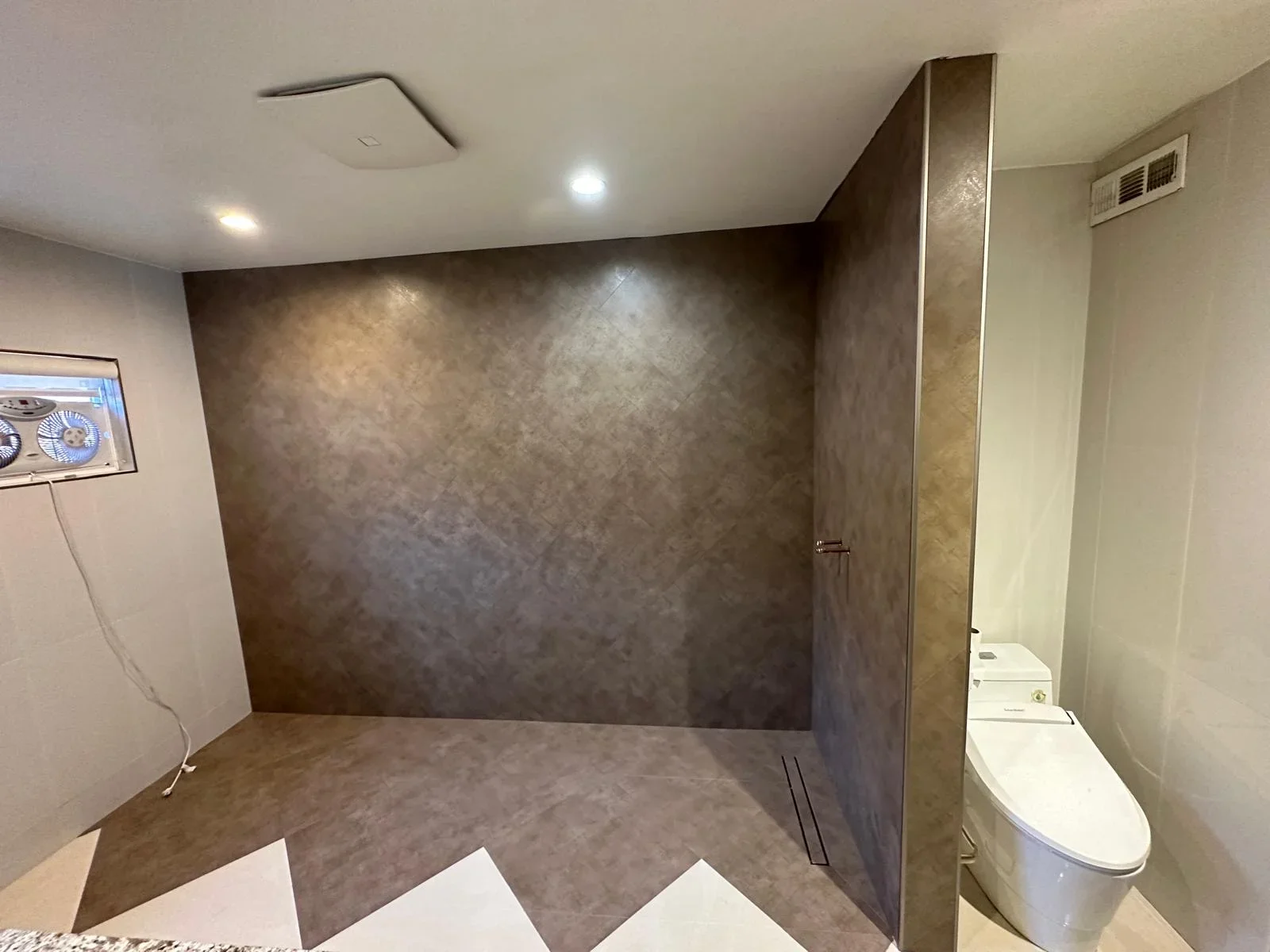 Modern bathroom with brown textured tile walls and geometric white floor tile pattern
