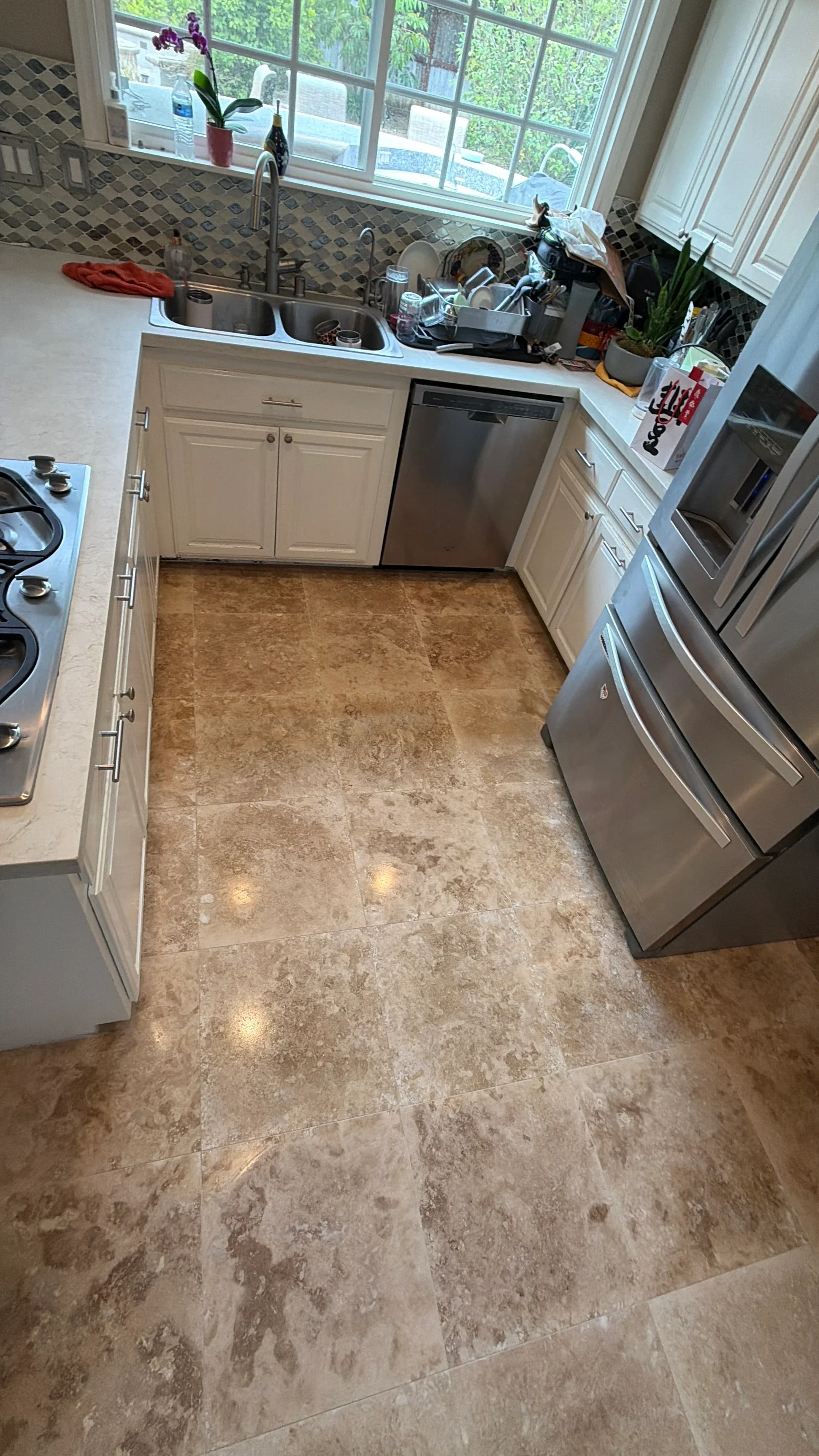 Kitchen with newly installed travertine tile flooring and white cabinetry