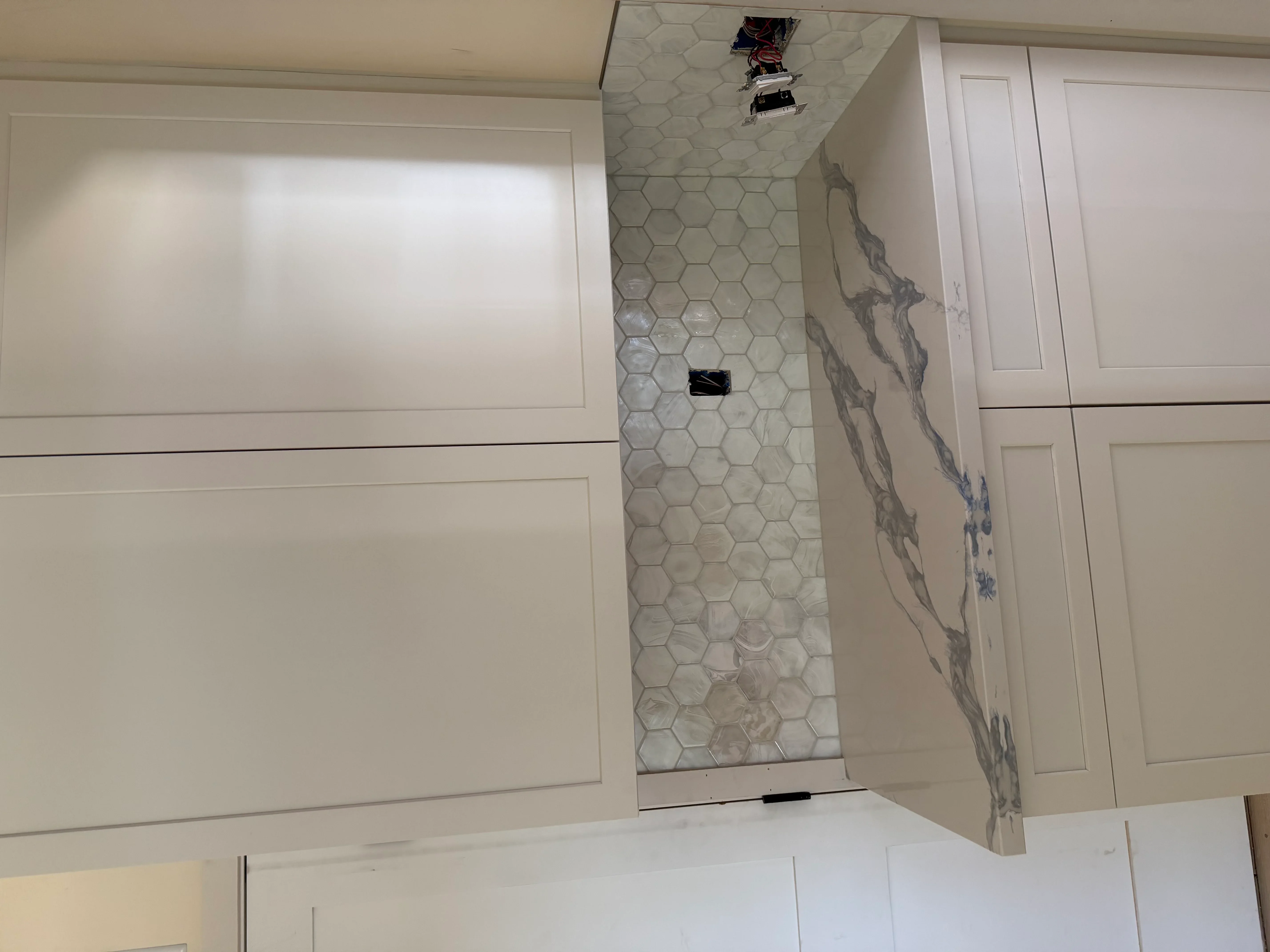 Bathroom shower with hexagon tile walls and marble-look porcelain tile accent