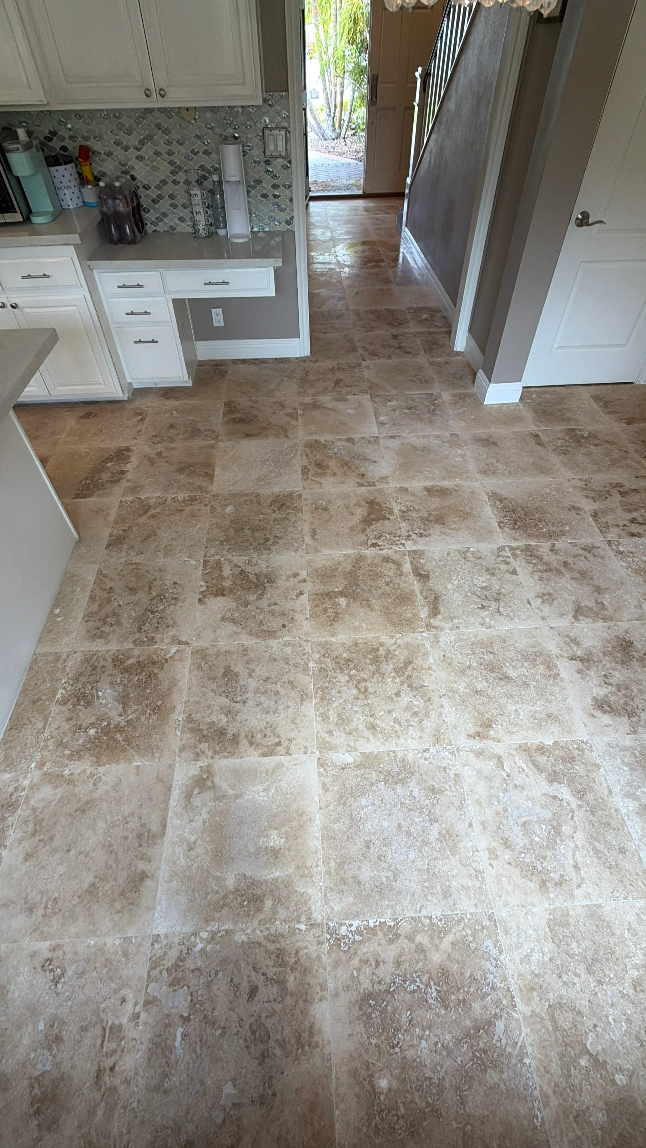 Travertine tile kitchen floor with white cabinets and geometric backsplash