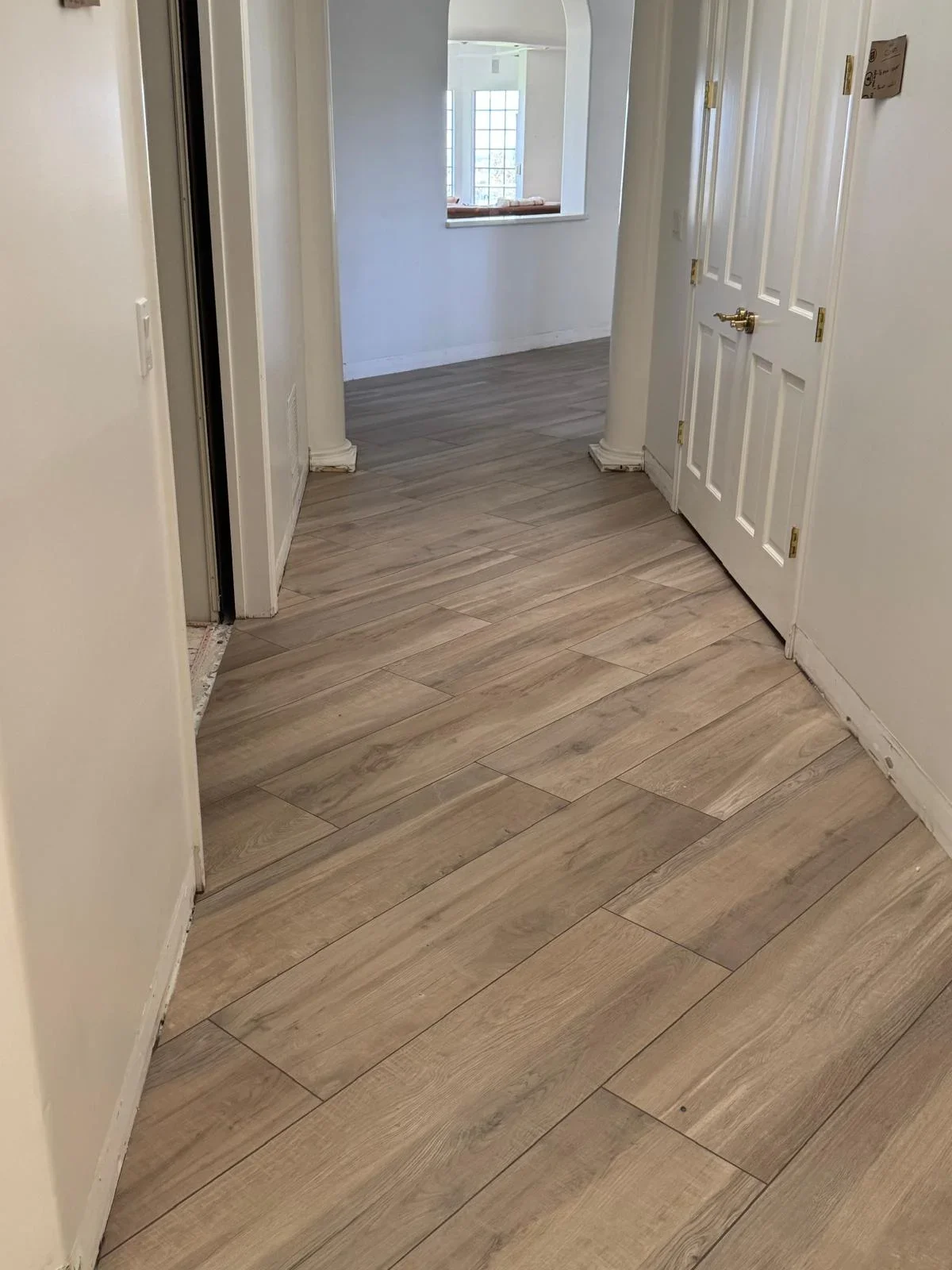 Hallway with herringbone wood-look tile flooring, white doors, and cream walls