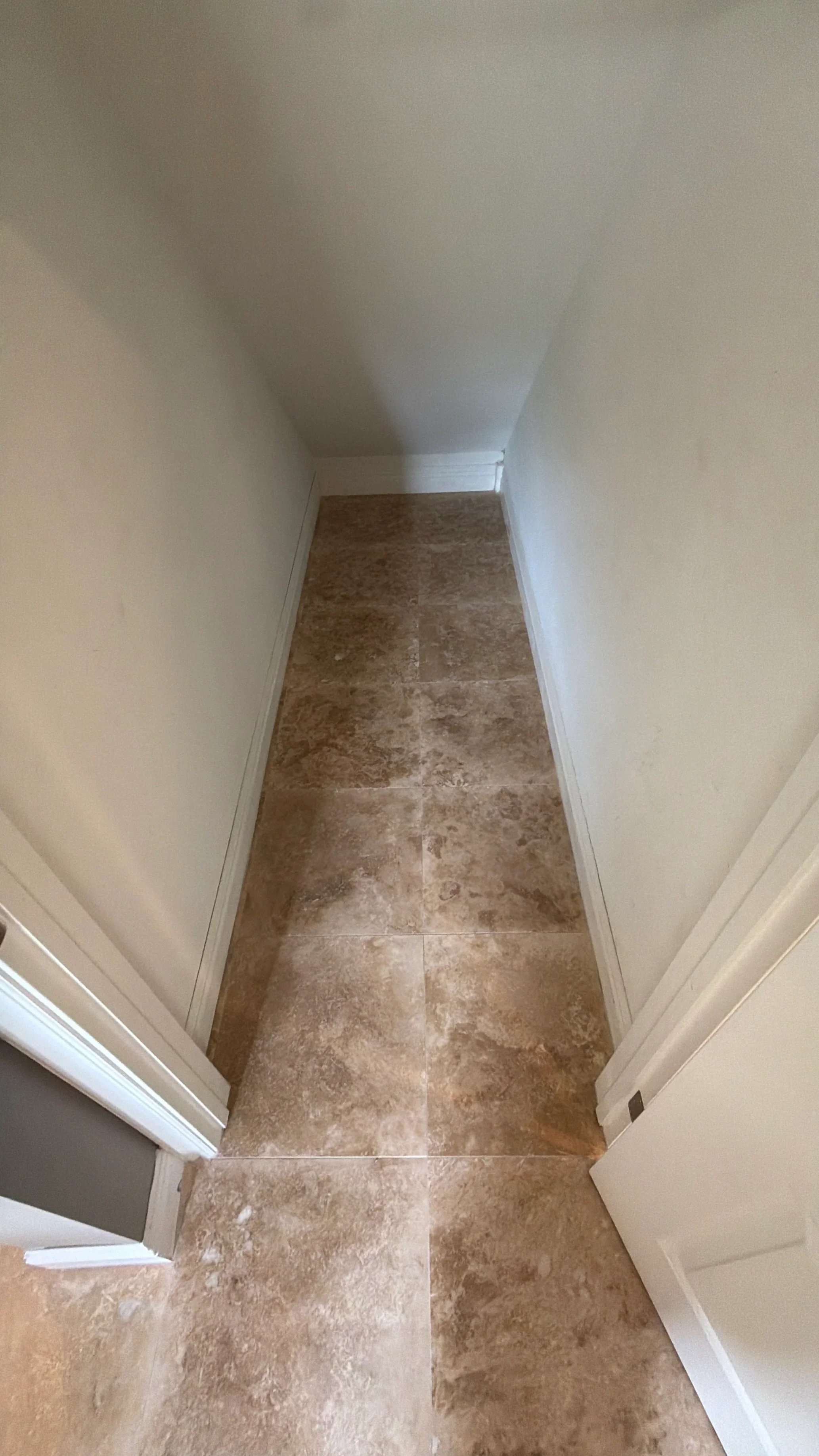 Hallway with travertine tile flooring, white walls and trim