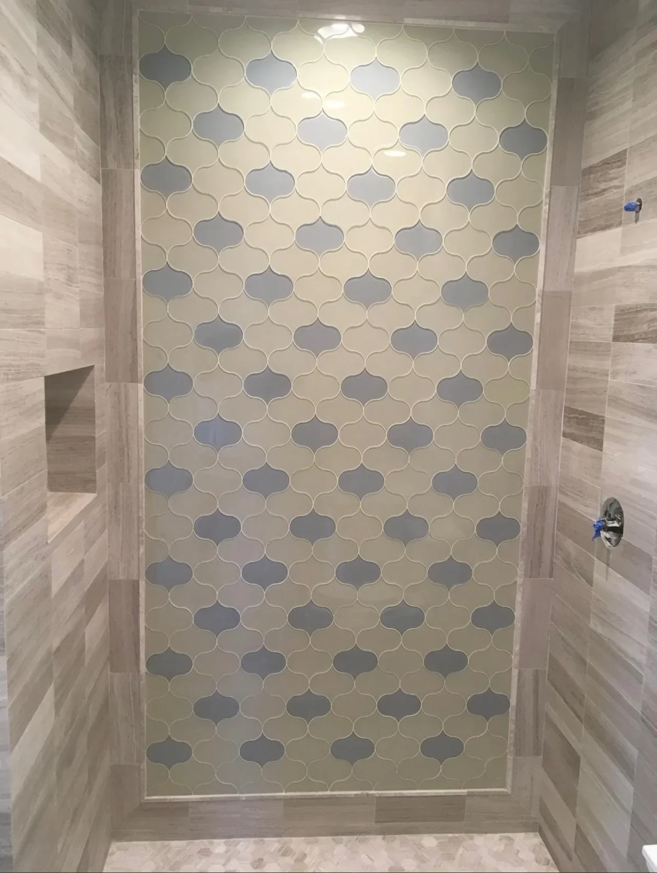 Shower surround with blue and cream Moroccan pattern tiles and wood-grain side walls