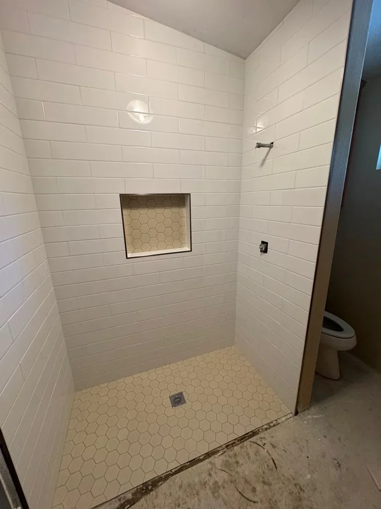White subway tile shower with hexagon floor tile and recessed niche