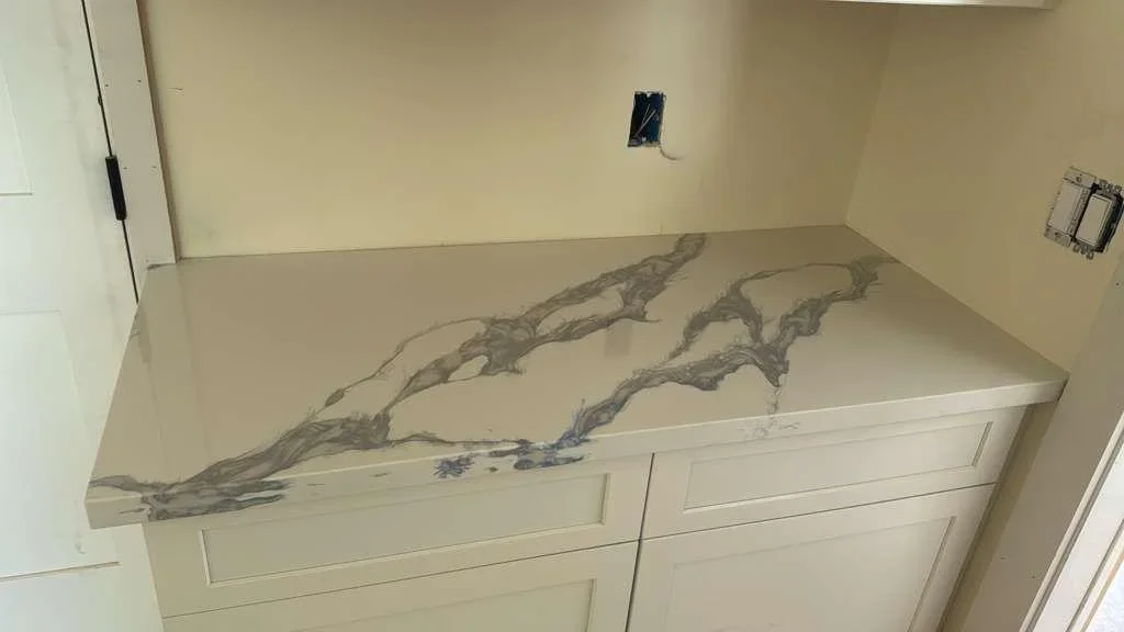 Gray and blue epoxy resin countertop with natural stone inlay over white cabinetry