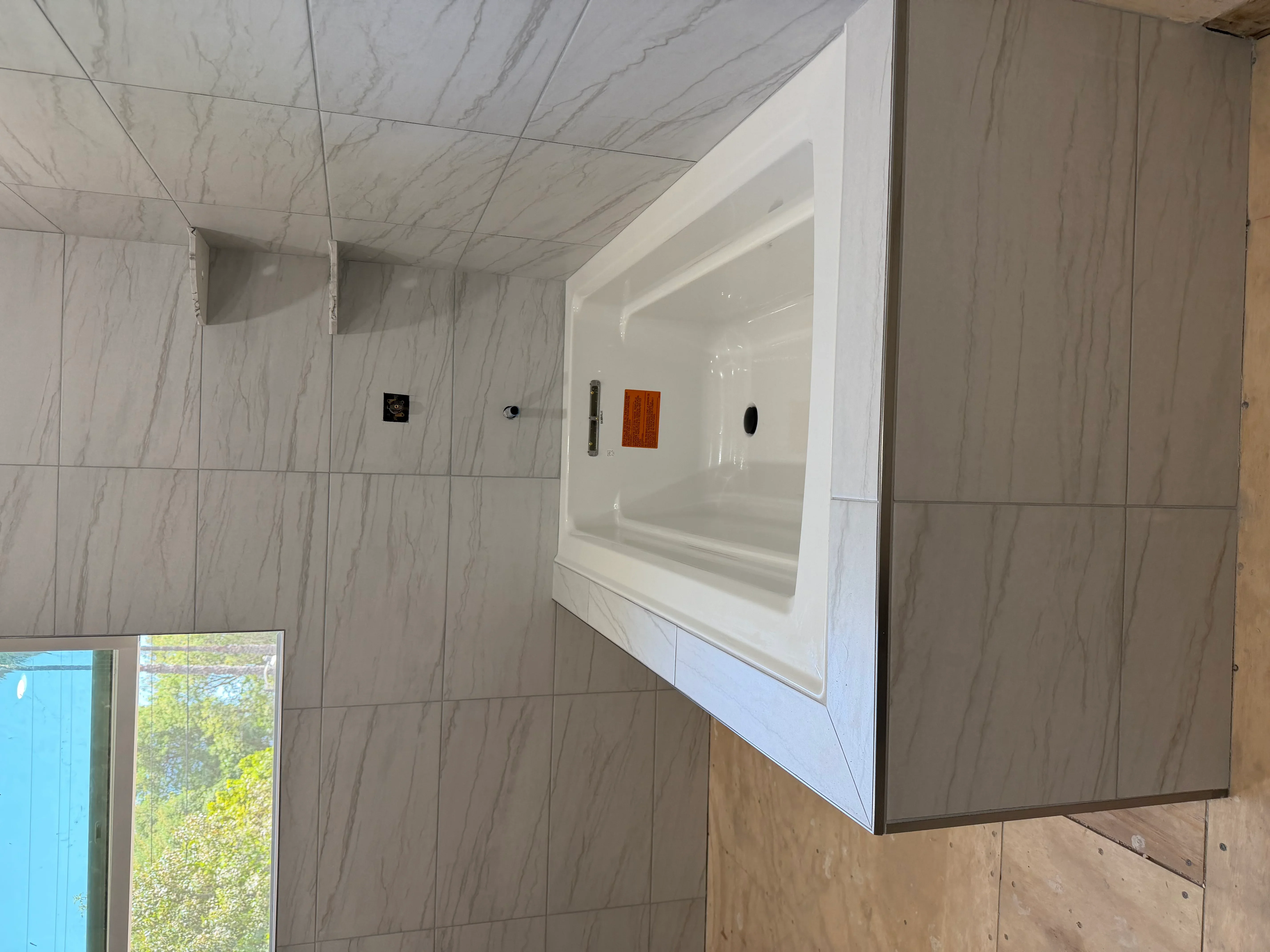 Marble tile shower with recessed niche and multiple fixture installations