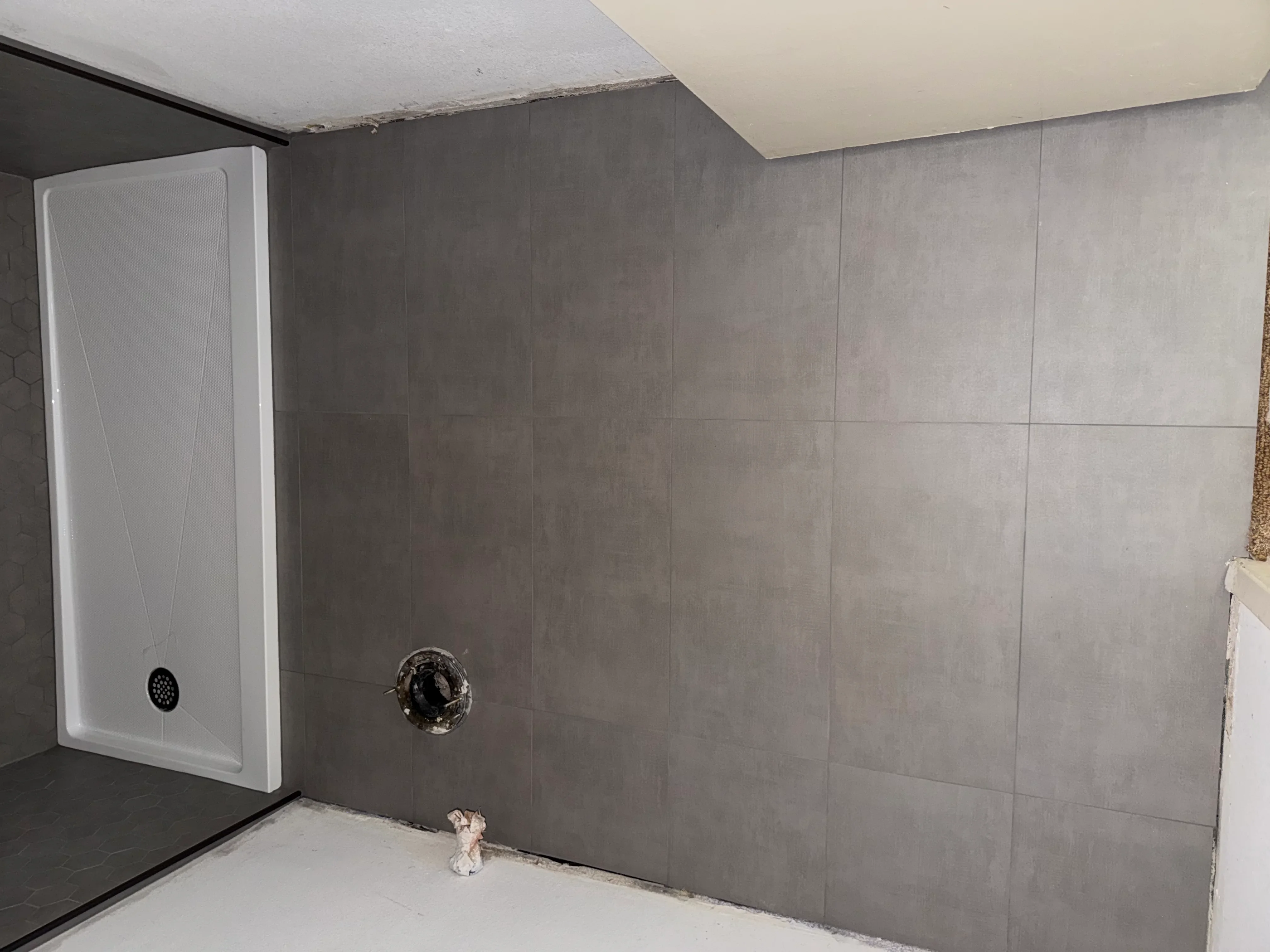 Gray ceramic tile shower walls with white acrylic pan and chrome showerhead installation
