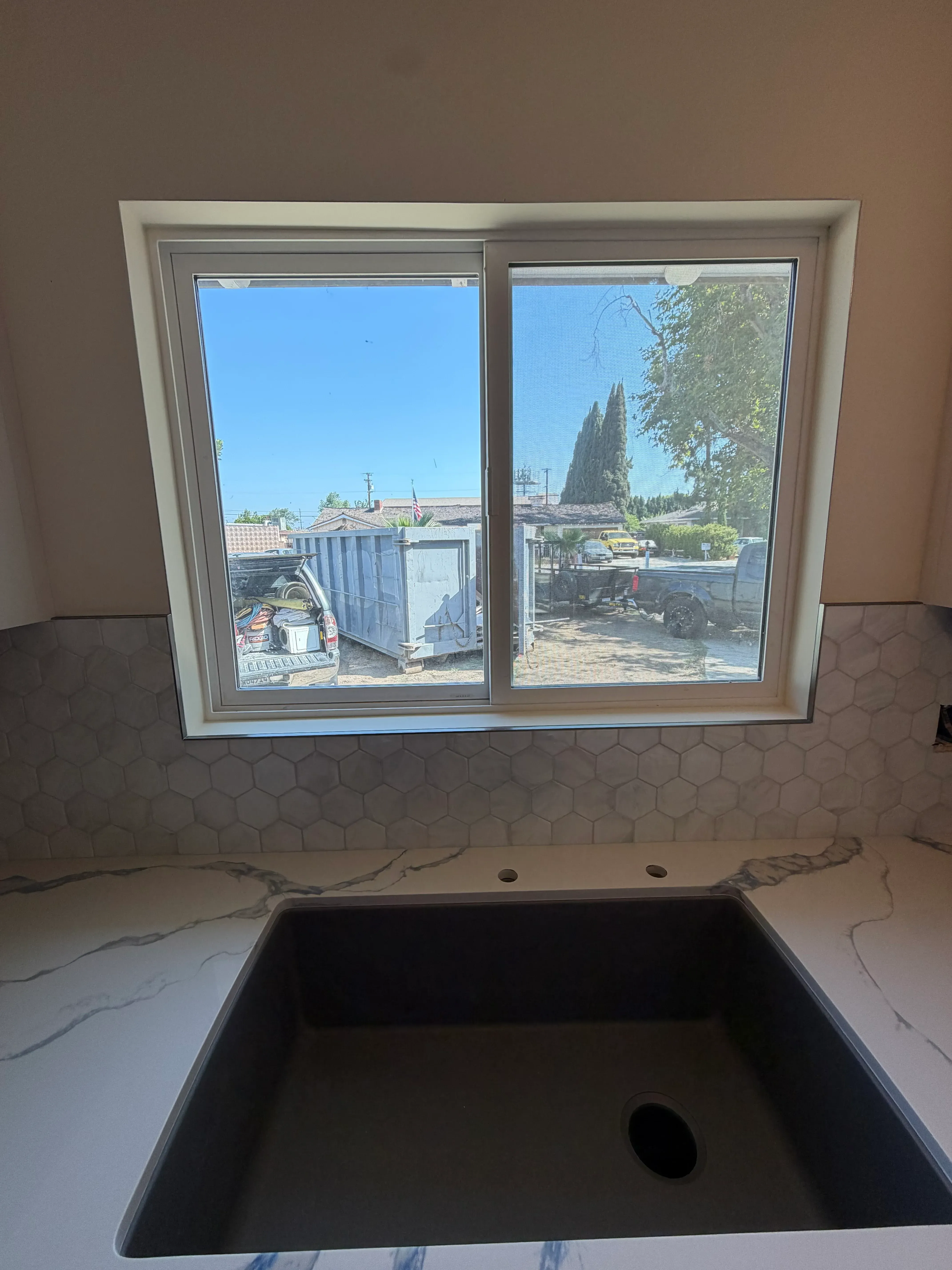 Bathroom with hexagonal tile accent wall and large window overlooking street