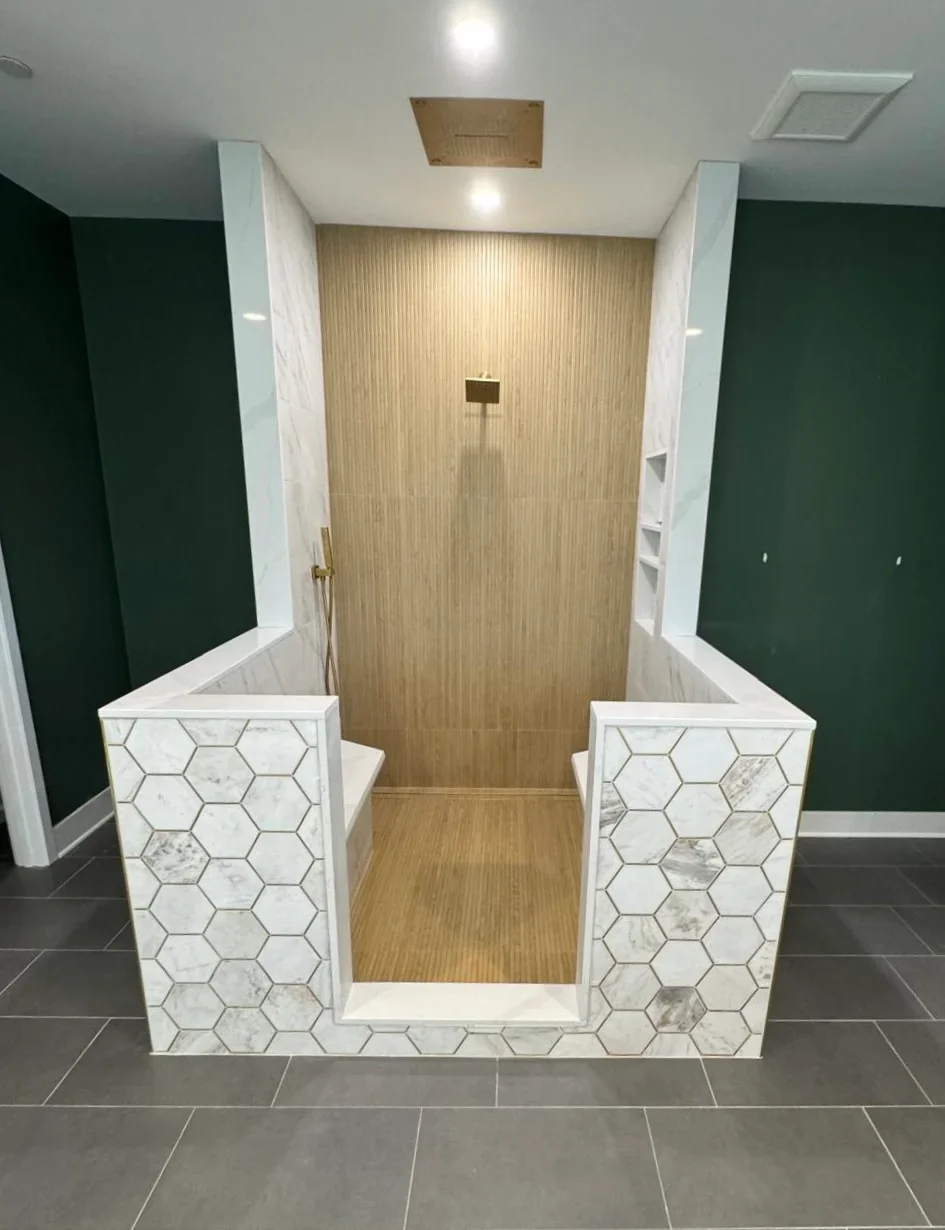 Modern bathroom shower with white hexagonal marble tile surround and wood-look tile interior