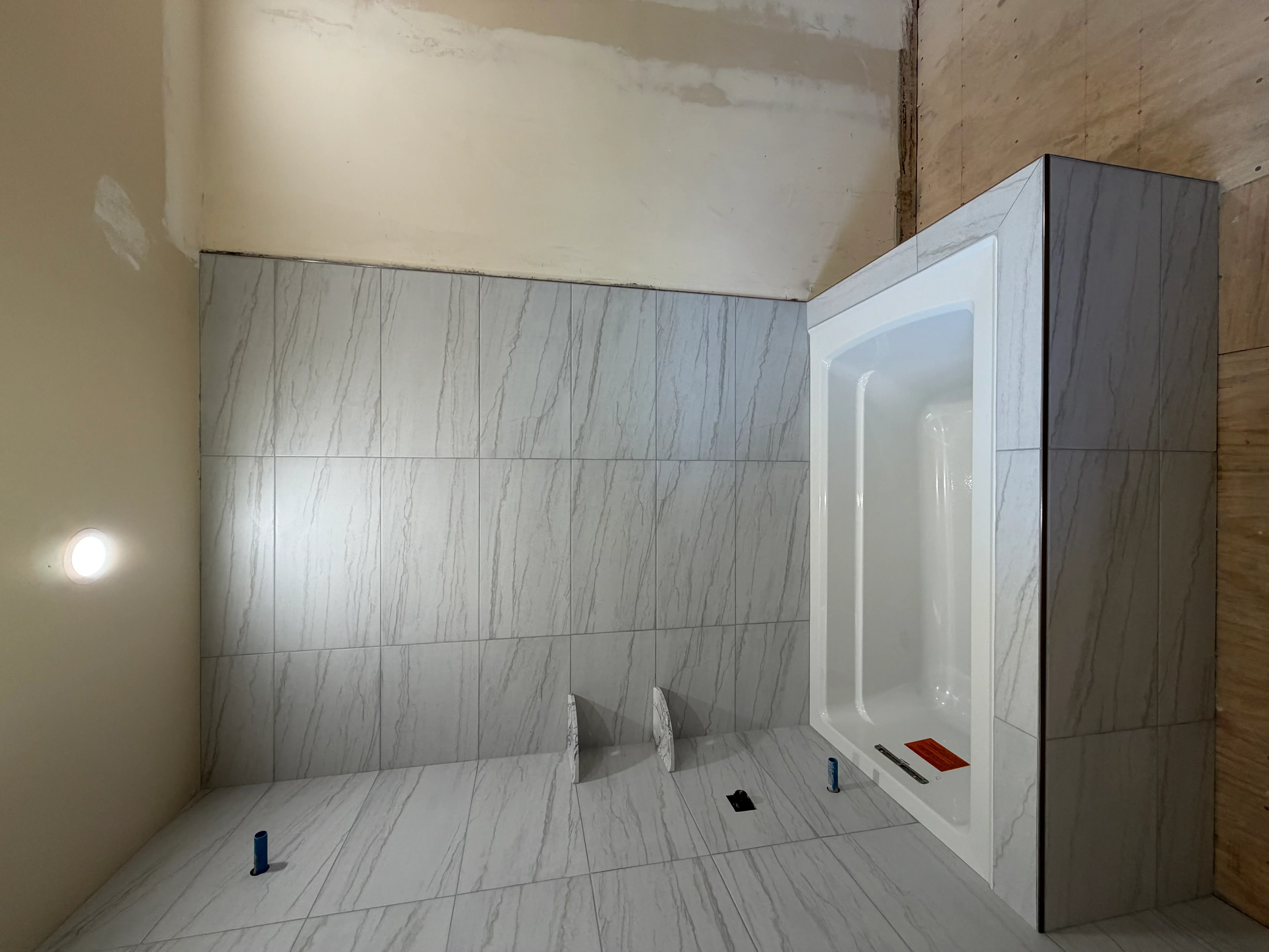 Marble-look tile shower with recessed niche and integrated lighting in progress