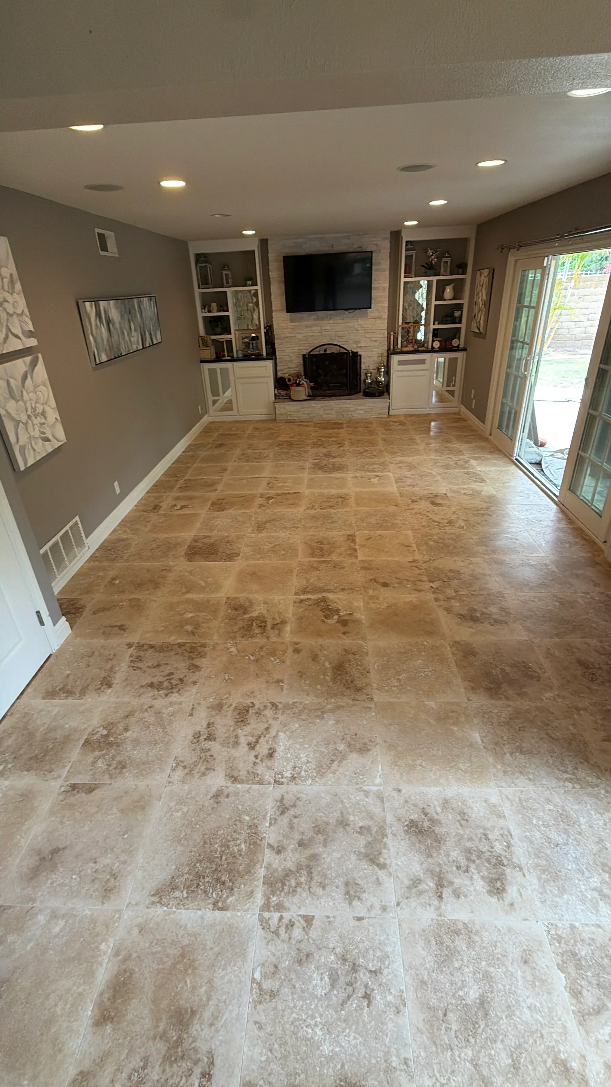 Spacious family room with installed travertine tile flooring and fireplace accent wall