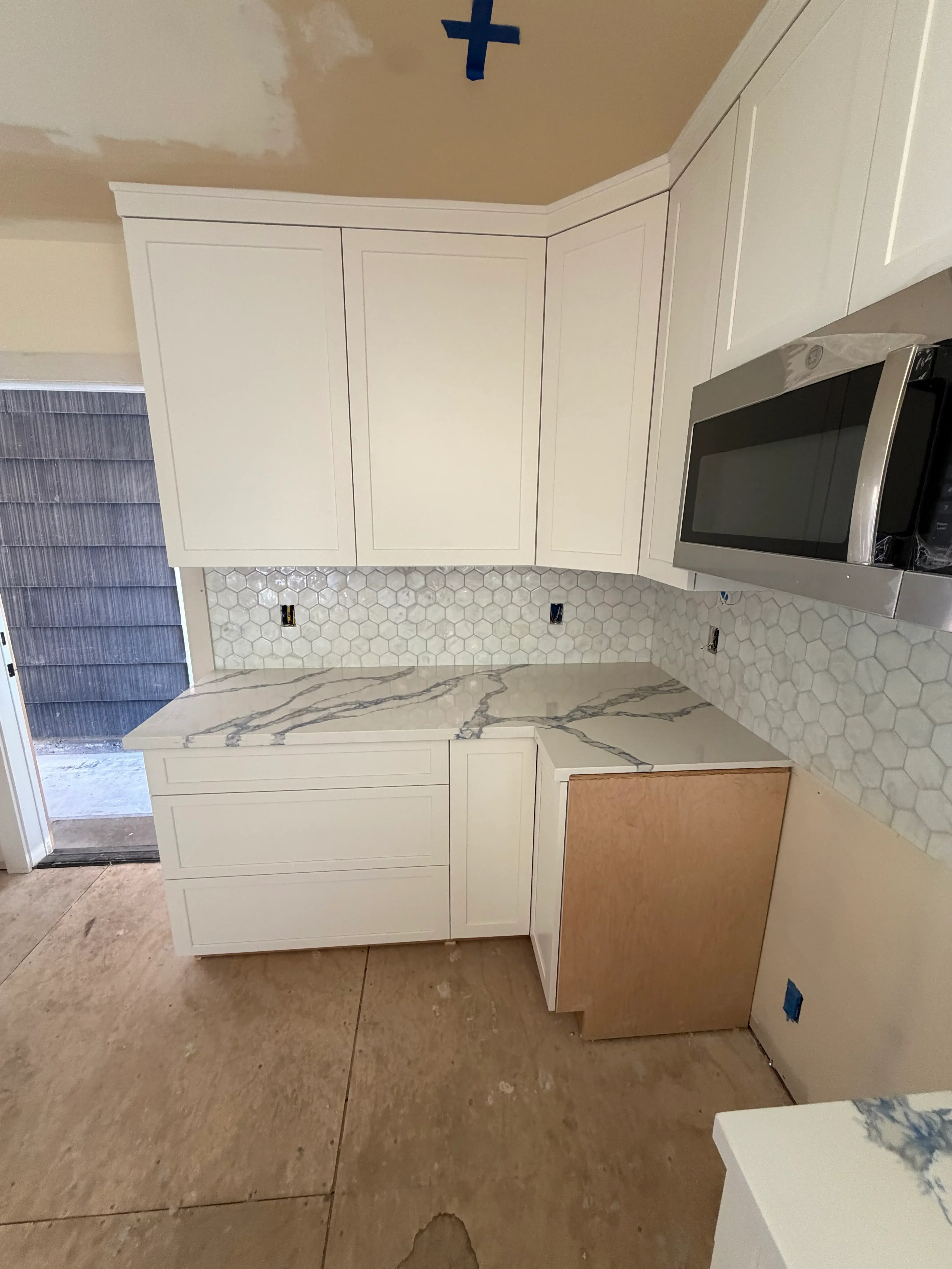 Bathroom with hexagonal marble tile floor, white vanity cabinets, and marble shower surround