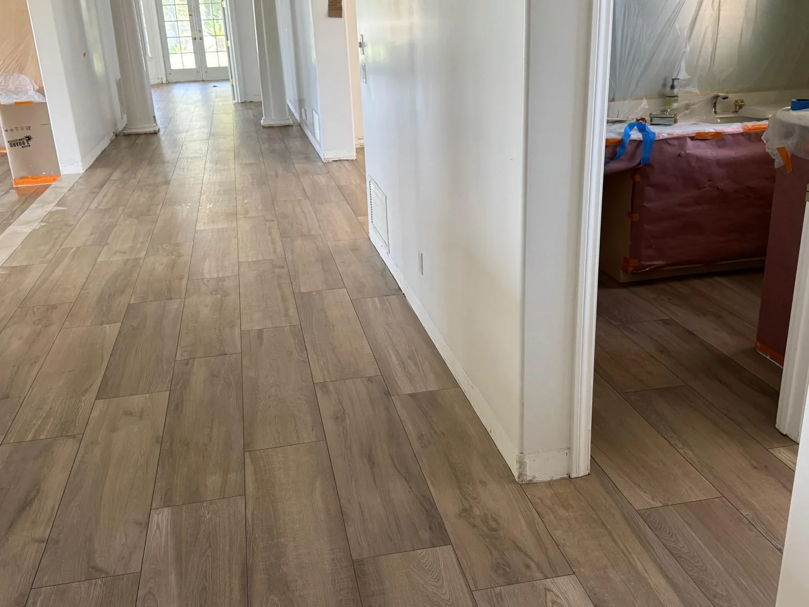 Wood-look porcelain tile flooring in running bond pattern installed throughout open residential space