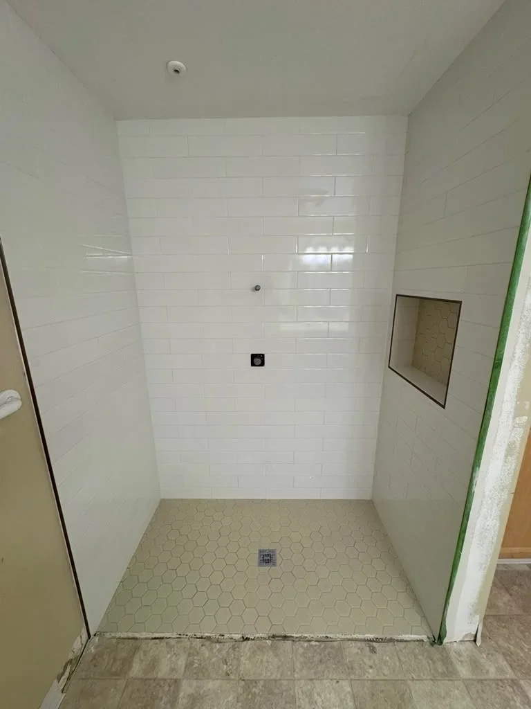 White subway tile shower with hexagonal floor tile and frameless glass door in modern bathroom