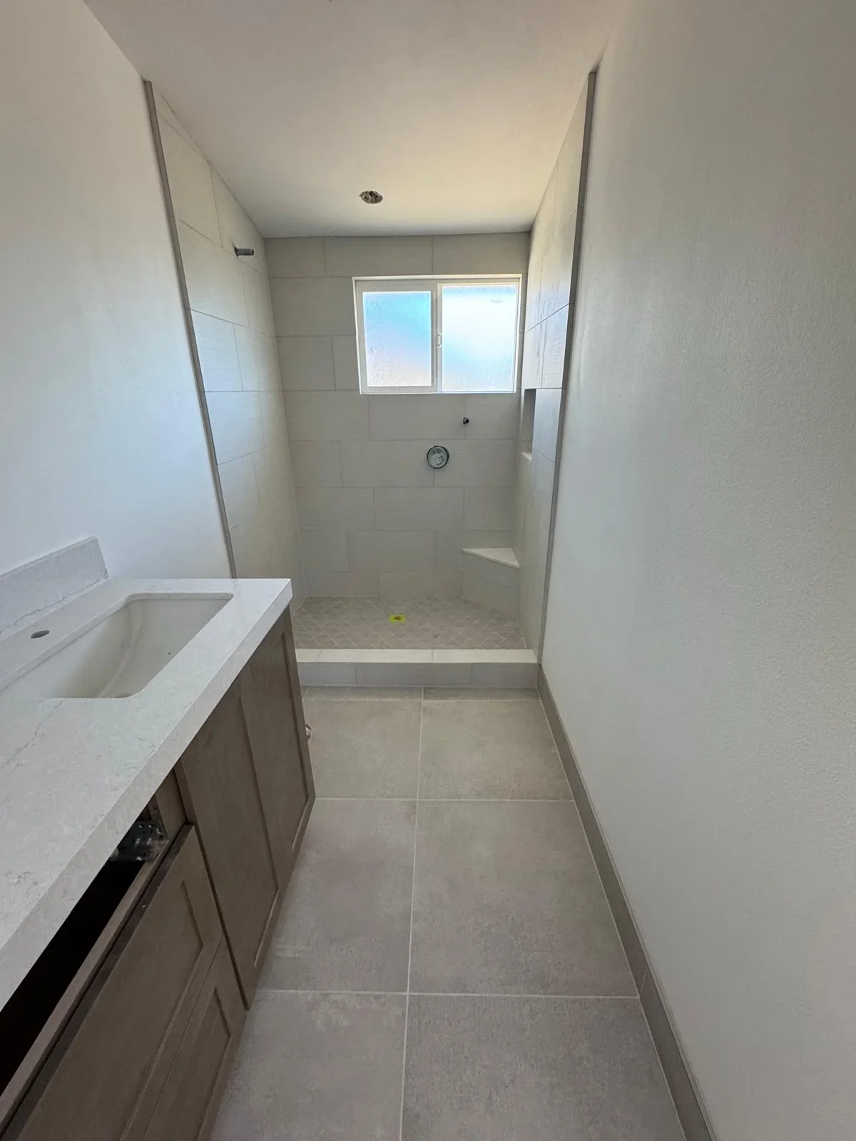 Modern bathroom with neutral tile flooring, glass shower enclosure, and marble vanity