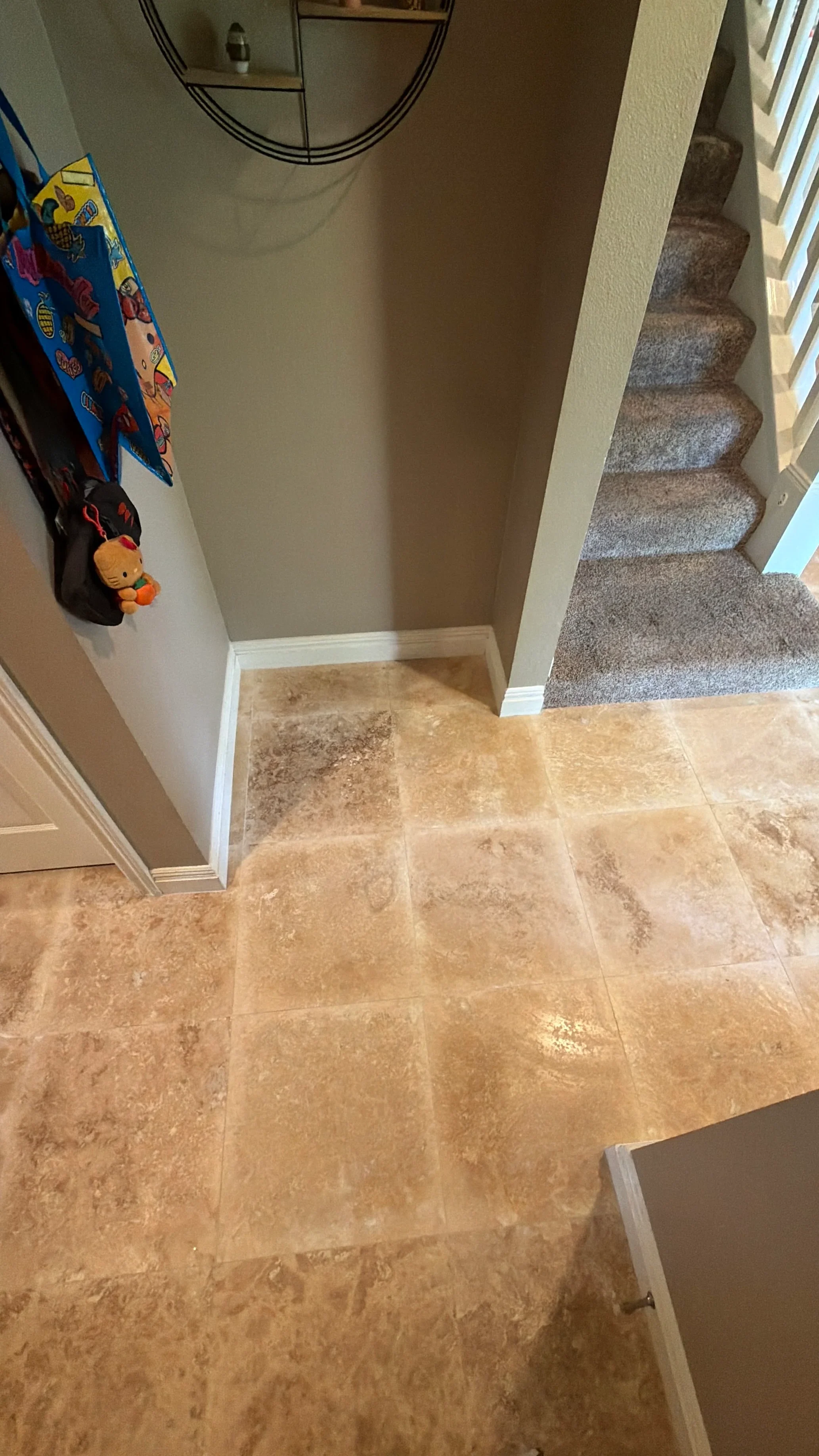 Travertine tile entryway with white trim and carpet transition to stairs