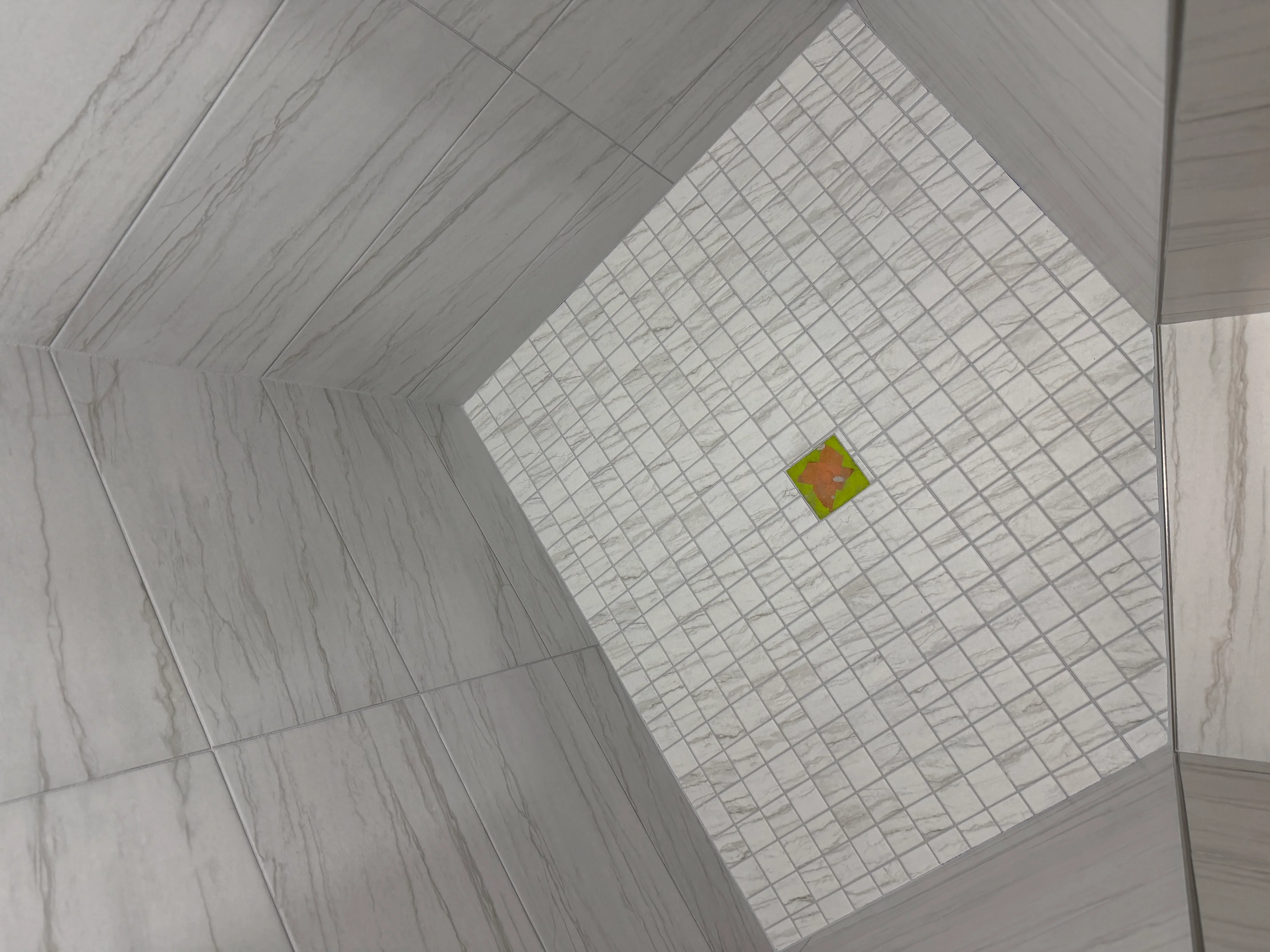 Bathroom floor with herringbone marble tiles and white mosaic center section with accent tile