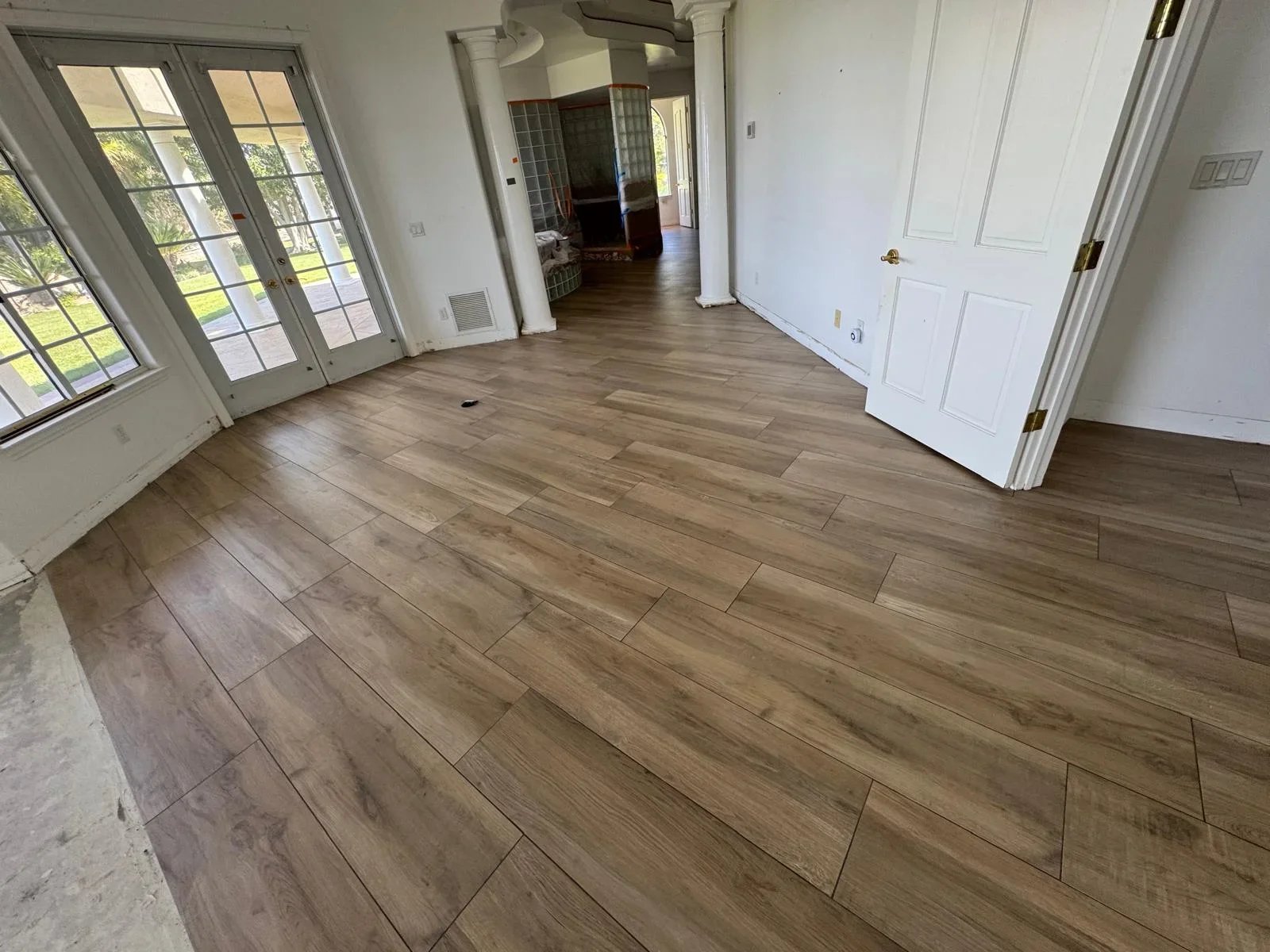 Wood-look tile flooring in staggered plank pattern throughout open living room with French doors