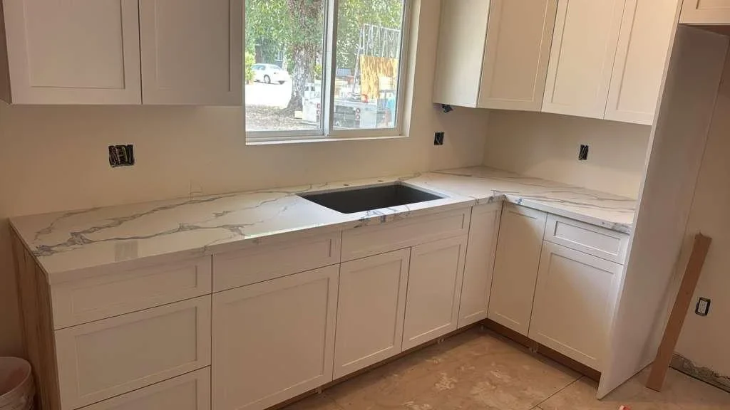 Kitchen countertop with marble-look quartz installed on white cabinetry with sink cutout