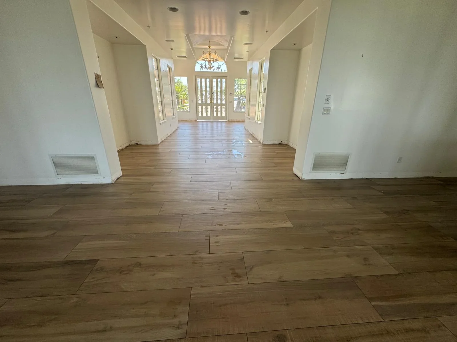 Spacious foyer with wood-look tile flooring, white walls, and natural light from front entrance