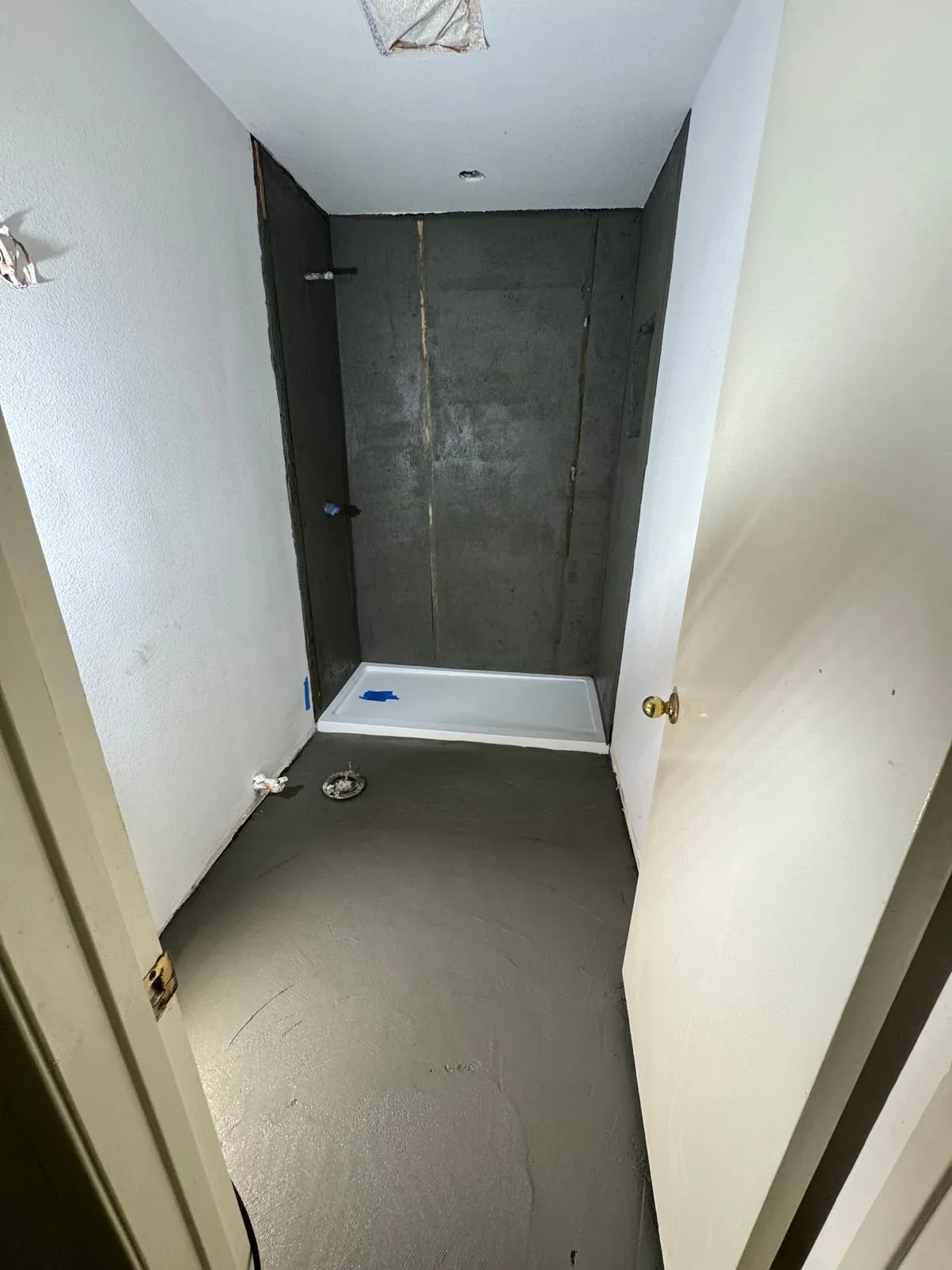 Dark gray tiled shower enclosure with white base pan and white drywall surround